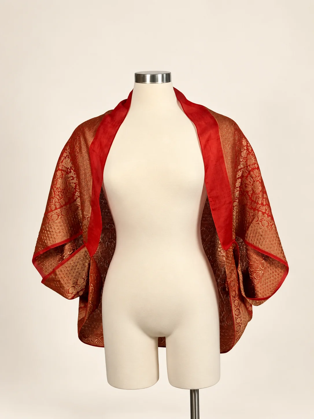 Front view of the red and gold Anjali Pallu Shrug draped on a cream dress form